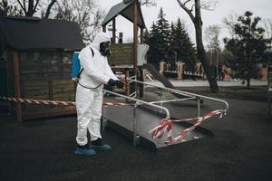 limpeza e desinfecção no playground no complexo da cidade em meio às equipes de epidemia de coronavírus para esforços de desinfecção prevenção de infecções e controle de traje de proteção e máscara epidêmica foto