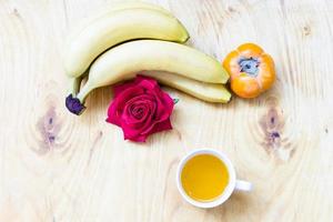 banana fresca e caqui no fundo da parede de tijolos e mesa de madeira, foto