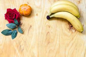 banana fresca e caqui no fundo da parede de tijolos e mesa de madeira, foto