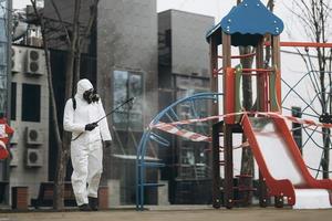 limpeza e desinfecção no playground no complexo da cidade em meio às equipes de epidemia de coronavírus para esforços de desinfecção prevenção de infecções e controle de traje de proteção e máscara epidêmica foto