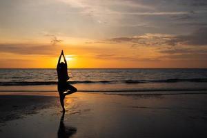 silhueta de homem meditar na praia ao pôr do sol foto