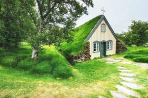 uma pequena igreja de madeira e cemitério hofskirkja hof, skaftafell, Islândia. pôr do sol cênico através das copas das árvores