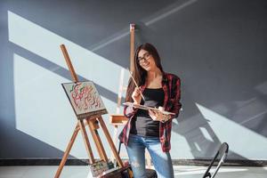 artista de menina muito bonita pinta na tela pintura no cavalete. foto