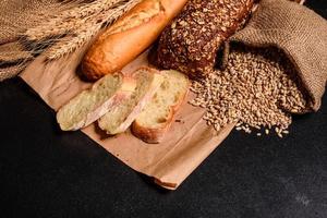 lindo pão fresco com grãos de trigo em um fundo escuro de concreto foto