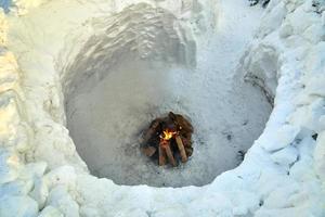 interior de uma casa de neve redonda de iglu com uma fogueira dentro foto