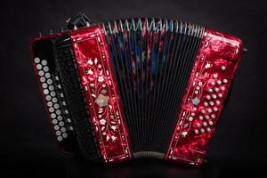 instrumentos folclóricos russos. vermelho bayan em um fundo preto. acordeão russo foto