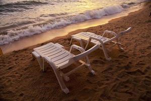 pôr do sol sobre o mar pataya beach tailândia com cadeira de praia foto