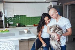 feliz casal lindo sentado na cozinha gato sorrindo. foto