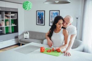 lindo casal jovem mói legumes juntos na cozinha. foto