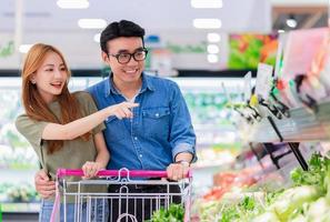 asiáticos recém-casados comprando mantimentos no supermercado foto