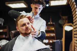 homem cabeleireiro fazendo corte de cabelo barba homens adultos no salão de cabeleireiro masculino foto