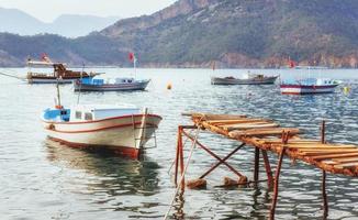 barcos perto do cais quebrado, colocando em uma água calma e tranquila do mar azul foto