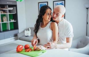 lindo casal jovem mói legumes juntos na cozinha. foto