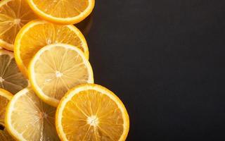 fatias de laranja e limão, isoladas em um fundo preto foto
