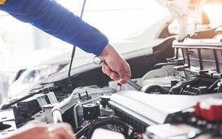 mãos do mecânico de automóveis com a chave inglesa na garagem foto