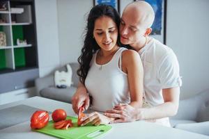 lindo casal jovem mói legumes juntos na cozinha. foto