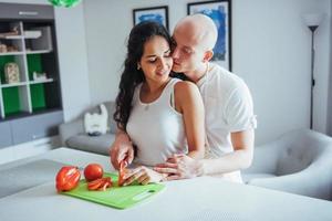 lindo casal jovem mói legumes juntos na cozinha. foto