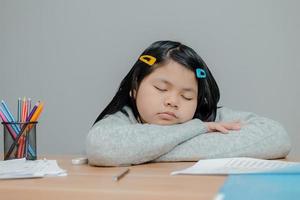 menina asiática dormindo na mesa foto