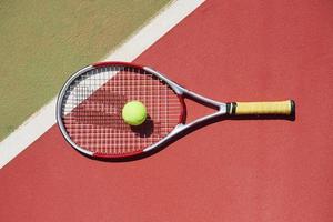 uma raquete de tênis e uma nova bola de tênis em uma quadra de tênis recém-pintada.