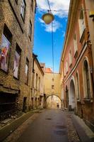 vilnius, lituânia - 20 de abril de 2015 ruas estreitas da cidade velha com arco, edifícios com paredes de tijolo e lâmpada de rua acima foto