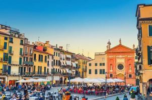 pádua, itália, 12 de setembro de 2019 igreja católica chiesa di san clemente, fileira de edifícios e mesas de restaurante na praça piazza plaza dei signori foto