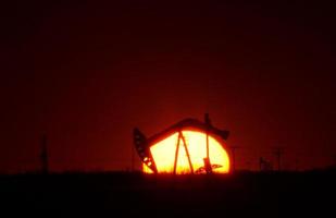 bomba de óleo no campo de saskatchewan ao pôr do sol foto