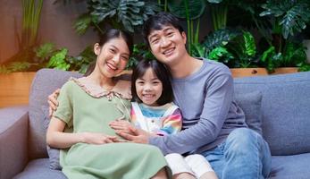 jovem família asiática com mãe grávida em casa foto