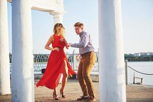 mulher bonita feliz no vestido vermelho e jovem dança de verão com lago ao fundo. contraste de cores vermelho e branco foto