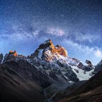 céu estrelado fantástico. paisagem de outono e picos nevados. cume caucasiano principal. vista para a montanha do monte ushba meyer, geórgia. Europa foto