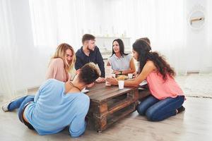 grupo de amigos criativos sentados à mesa de madeira. pessoas se divertindo jogando jogo de tabuleiro foto