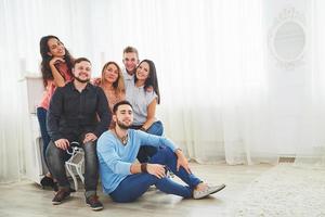 retrato de grupo de meninos e meninas multiétnicas com roupas coloridas da moda segurando amigo e posando em uma parede de tijolos, pessoas de estilo urbano se divertindo, conceitos sobre juventude e estilo de vida foto