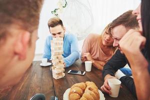 grupo de amigos criativos sentados à mesa de madeira. pessoas se divertindo jogando jogo de tabuleiro foto