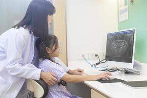 dentista feminina explicando o raio-x dos dentes para uma garotinha na clínica odontológica, check-up dos dentes e conceito de dentes saudáveis foto