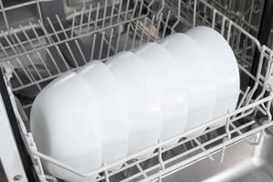 pratos brancos na máquina de lavar louça. lição de casa com conceito de máquina de lavar louça foto
