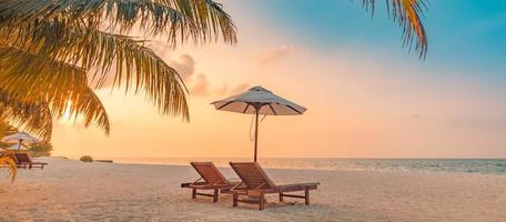 incrível praia romântica. cadeiras na praia de areia perto do mar. conceito de férias de férias de verão para turismo. paisagem de ilha tropical. cenário tranquilo da costa, relaxe o horizonte à beira-mar, folhas de palmeira foto