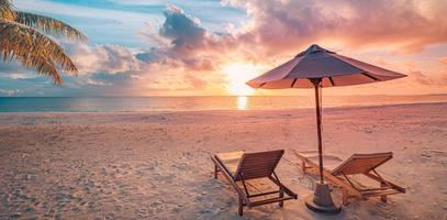 incrível praia romântica. cadeiras na praia de areia perto do mar. conceito de férias de férias de verão para turismo. paisagem de ilha tropical. cenário tranquilo da costa, relaxe o horizonte à beira-mar, folhas de palmeira foto