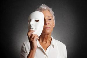 mulher mais velha séria, revelando o rosto por trás da máscara foto