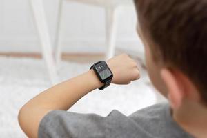 menino monitorando diabetes do conceito de relógio. aplicativo exibe o nível de glicose no sangue lido de um sensor à mão foto