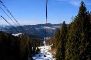 panorama de montanhas de inverno com pistas de esqui e teleféricos em um dia nublado foto