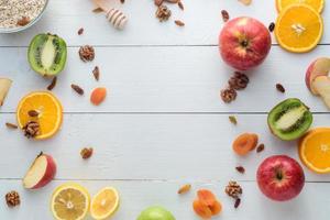 maçãs, kiwis, frutas secas, laranjas e maçãs. conceito de alimentação saudável. tiro em uma mesa de madeira branca. foto