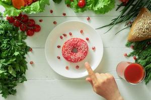 um delicioso donut está em um prato e come para comê-lo. problemas de nutrição adequada e o conceito de escolher entre alimentos saudáveis e não saudáveis foto