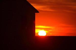 pôr do sol atrás de uma antiga escola rural na pitoresca saskatchewan foto