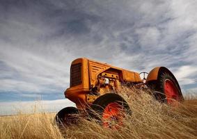 tumbleweeds empilhados contra o trator abandonado foto