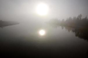 sol refletido na água durante uma manhã de neblina saskatchewan foto