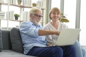 feliz casal sênior caucasiano usando laptop em casa foto