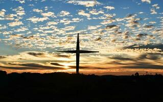 silhueta da cruz cristã e turbinas eólicas ao pôr do sol foto