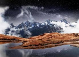 fantástico céu estrelado no lago de montanha koruldi. pitoresca noite superior svaneti, geórgia europa. montanhas do cáucaso foto