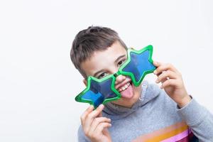 um menino alegre em óculos engraçados mostra a língua. conceito de celebração do dia da mentira foto