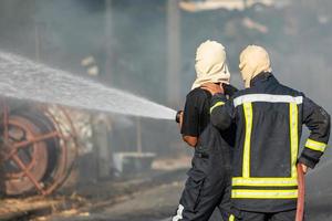 bombeiro pulverizando água da mangueira de água grande para evitar incêndio foto