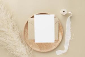 maquete de convite de cartão em branco no envelope marrom com grama dos pampas em fundo bege, composição mínima do local de trabalho da mesa, postura plana, maquete foto